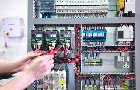 An electrician wiring breakers inside a commercial control panel
